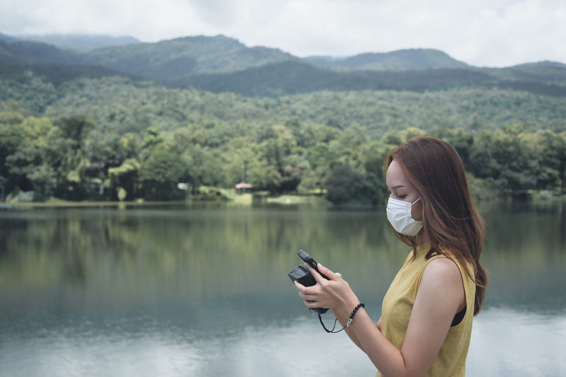 Young woman traveller using smart phone ,surrounding by lake and mountain