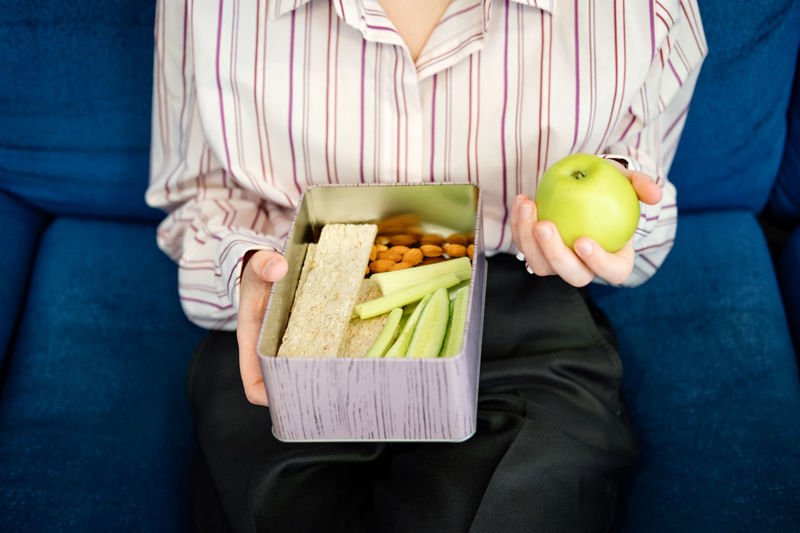 Healthy snack for office worker. woman hands with lunch box at workplace during lunch break