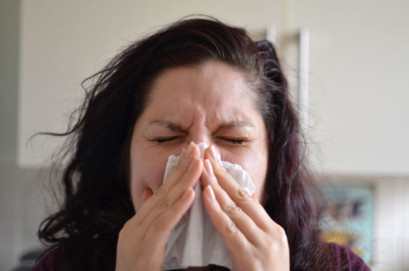 Woman blowing her nose with tissue at home