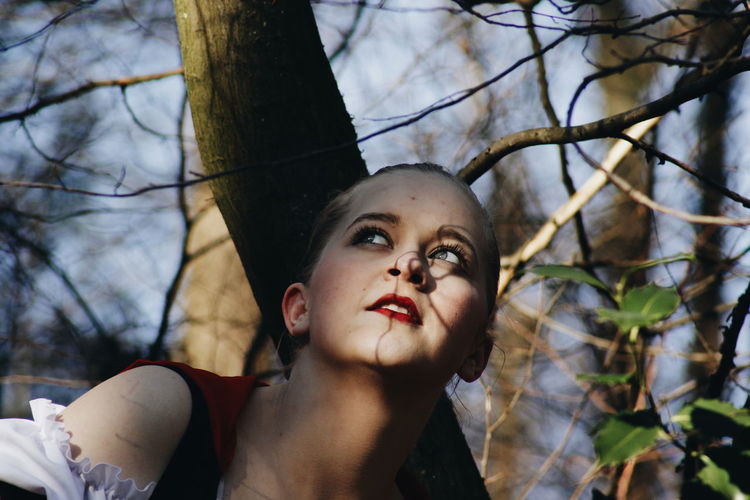 Close-up of young woman against tree trunk