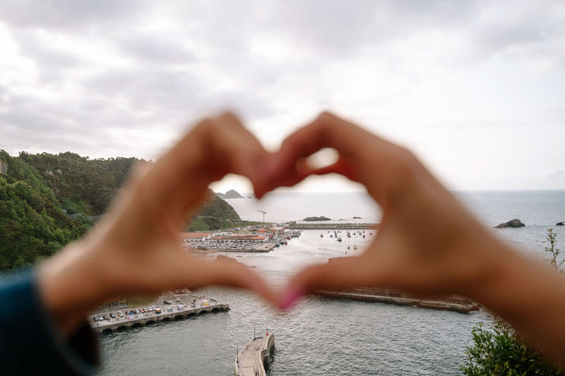 Midsection of hands making heart shape against sea