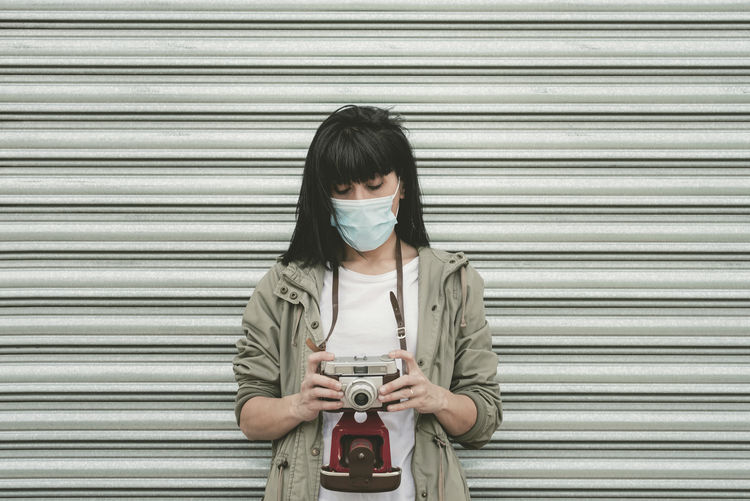 Portrait of senior woman standing against closed shutter