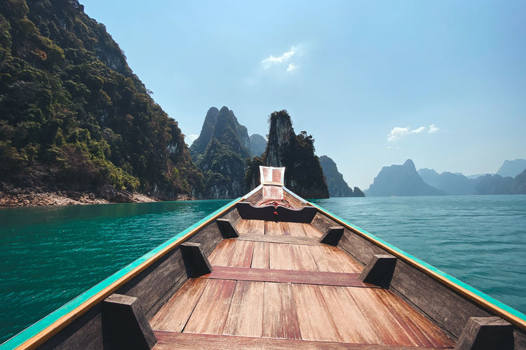 Rowboat in sea against rock mountains