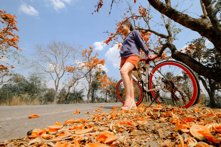 Woman with bicycle on leaves during autumn