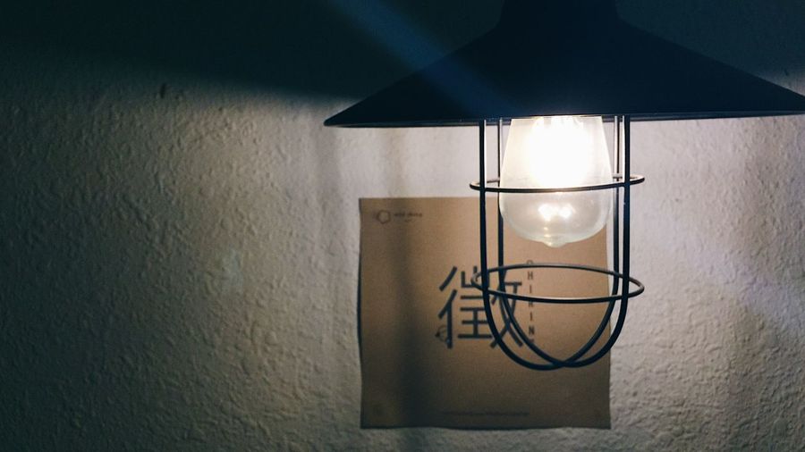 Close-up of illuminated light bulb hanging at home