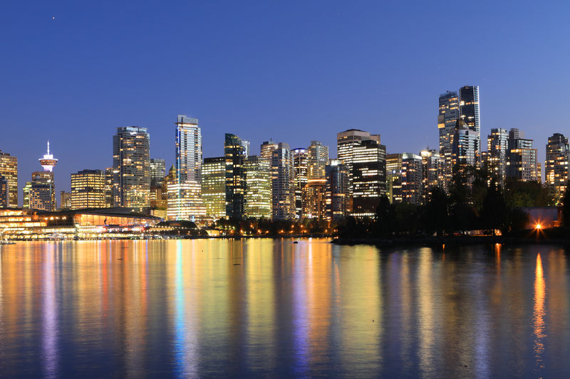 Illuminated buildings in city against clear sky