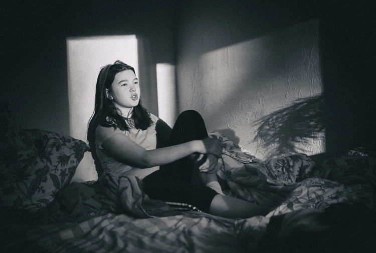 Thoughtful teenage girl relaxing on bed