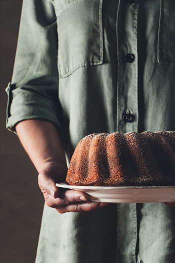 Midsection of man holding bundt cake in plate