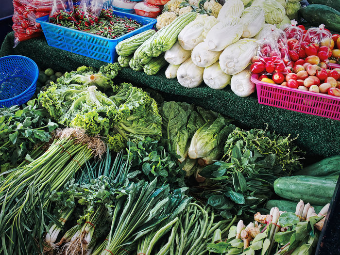 Pile of various kinds of fresh green herbal vegetables for sale at market stall