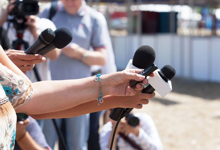 Cropped image of journalists holding microphones