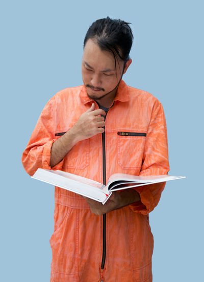 Mid adult man holding book against blue background