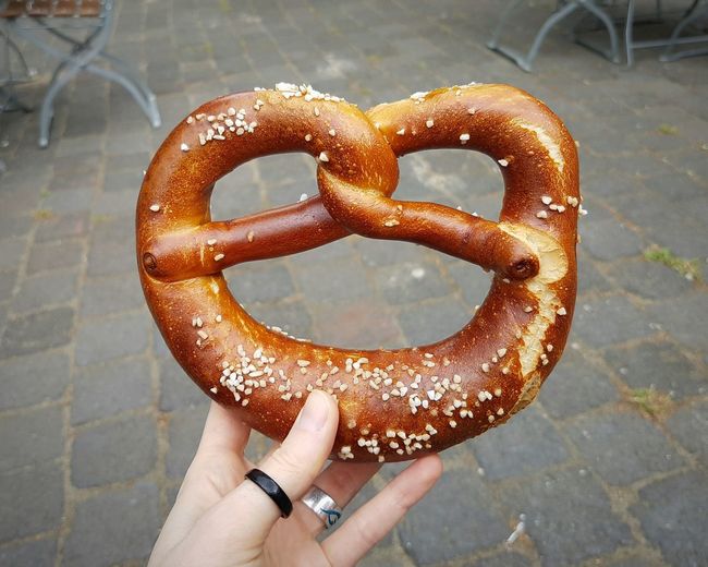 Cropped hand holding pretzel on footpath