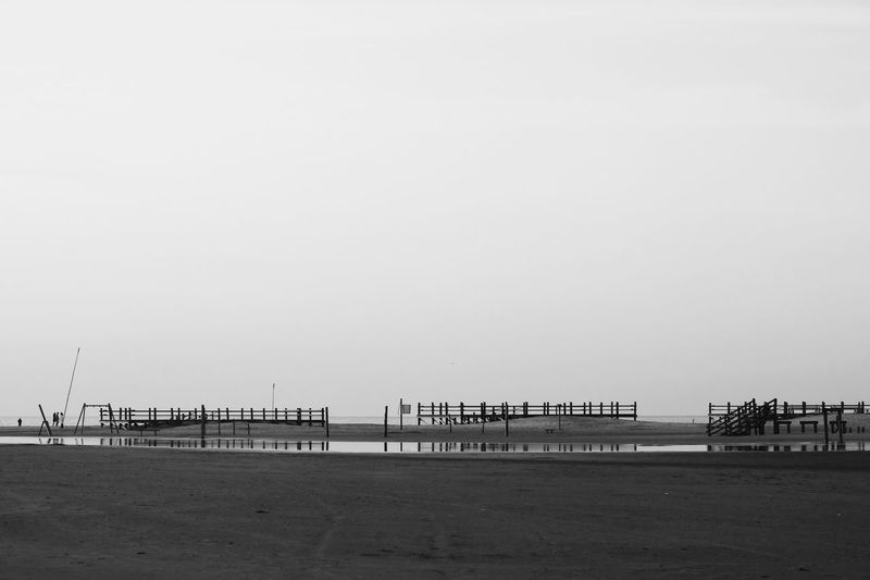Pier on beach against clear sky