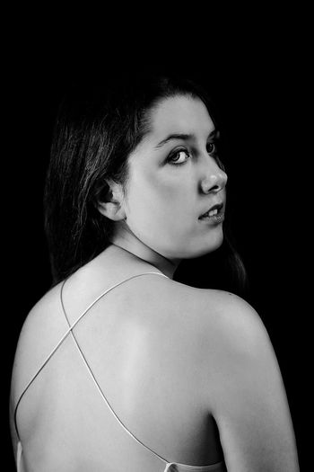 Rear view of woman looking over shoulder against black background