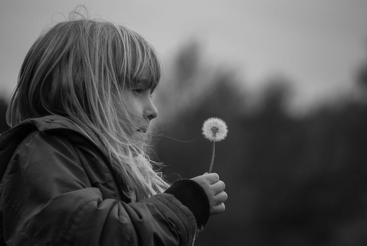 Close-up of girl with flower against sky