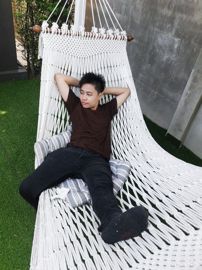 High angle view of young man relaxing on hammock in yard