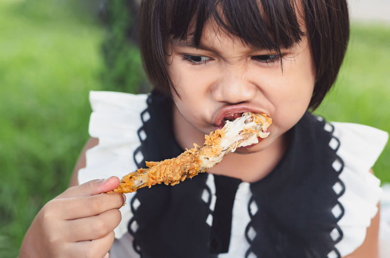 Close-up of girl eating meat outdoors