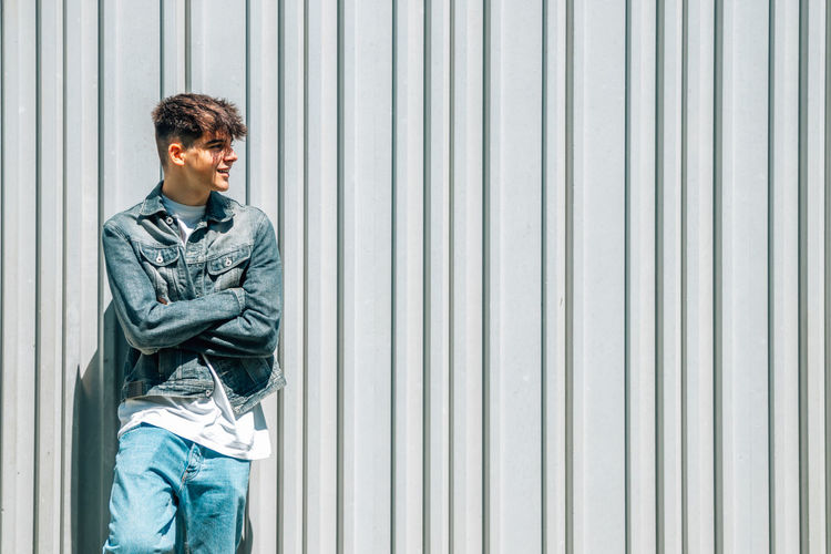 Portrait of young man standing against wall