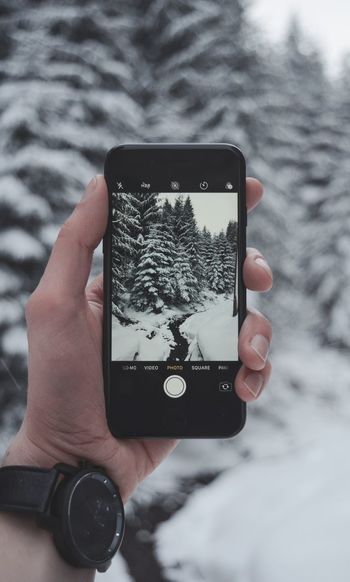 Close-up of hand holding smart phone in snow
