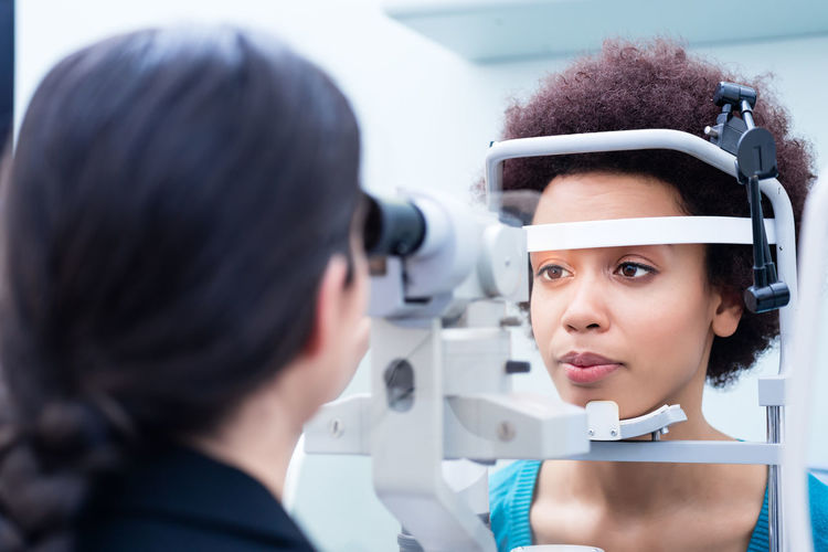 Ophthalmologist examining woman wearing eye test equipment 
