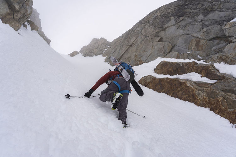 Low angle view of ski mountaineer climbing mountain during winter