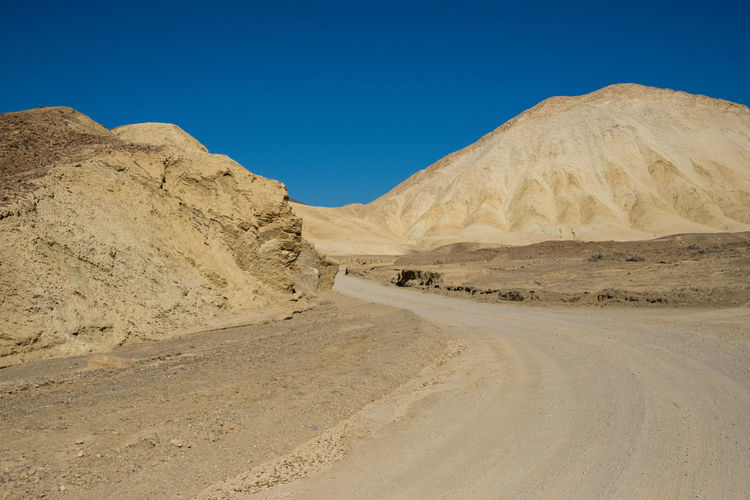 Road in desert against clear blue sky
