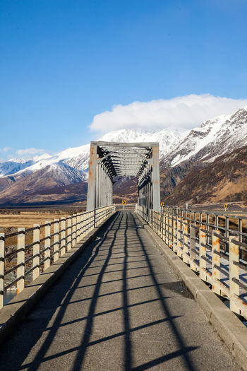 Walkway leading towards snowcapped mountains against sky