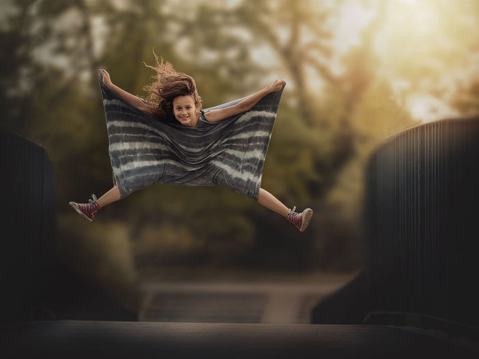 Portrait of girl levitating over footbridge