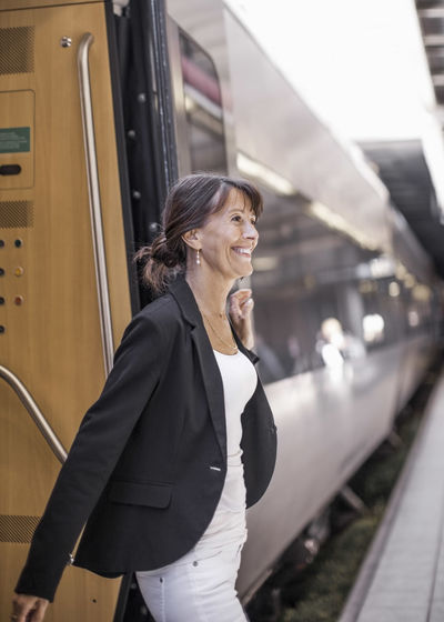 Side view of woman with train at railroad station