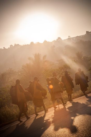 Monks walks on village road against glowing sunlight