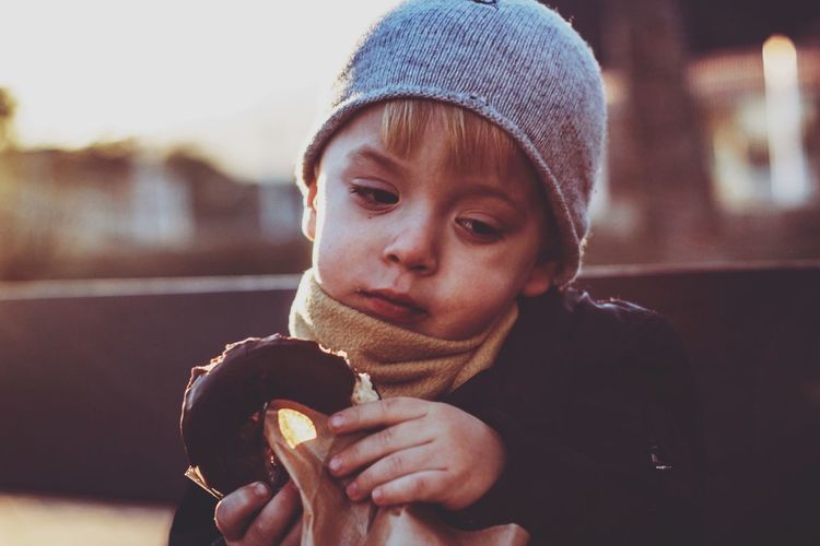 Cute boy holding donut during sunset