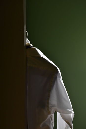 Close-up of white shirt hanging on white closet door