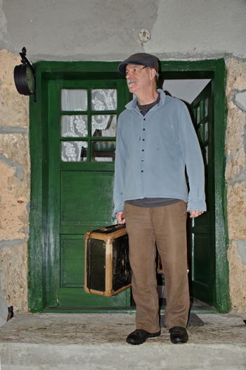 Portrait of senior man standing in the doorway with vintage suitcase