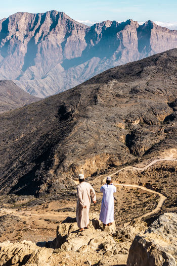 Rear view of people walking on desertic mountains