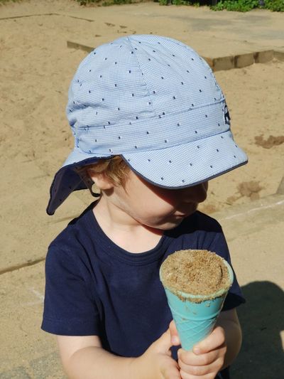 Girl holding sand in plastic ice cream cone at beach