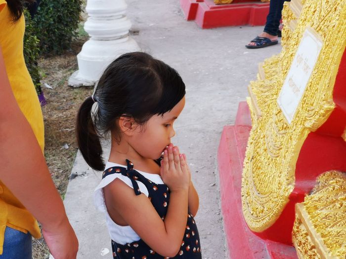 Close-up of girl praying while standing at temple