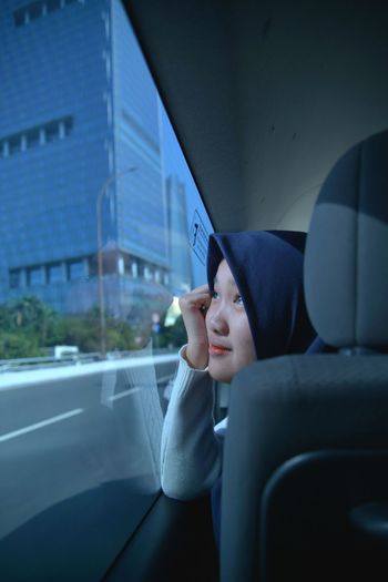 Close-up of teenage girl wearing hijab looking through window in car