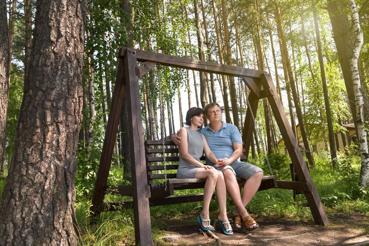 An adult couple in love, a man and a woman, are sitting on a wooden 