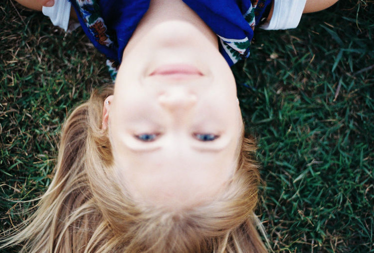 High angle portrait of boy lying on grassy field