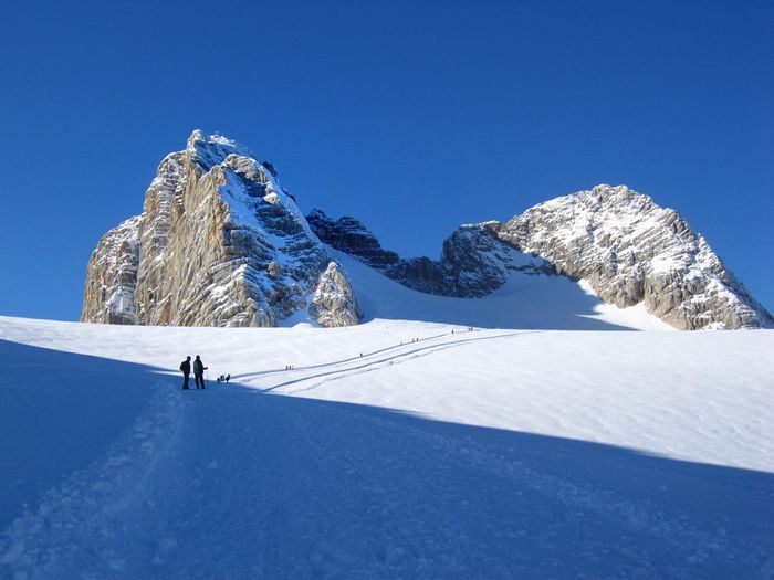 People standing on dachstein mountains against clear sky