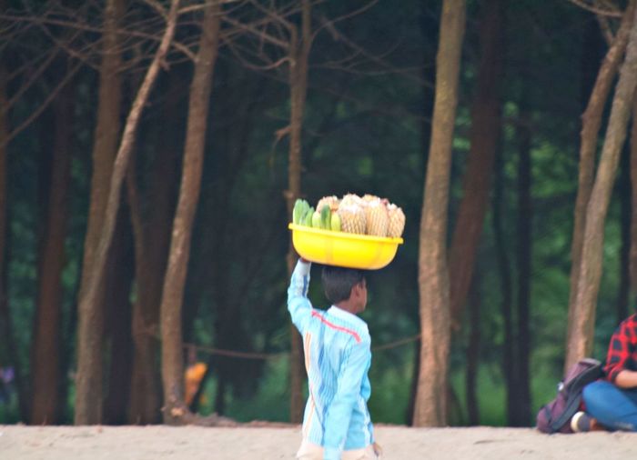 Side view of woman with umbrella against trees