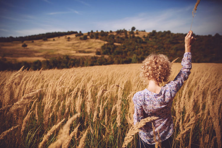Rear view of woman in farm field against sky