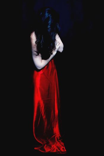 Woman in red gown with long hair against black background