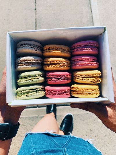 Low section of woman holding macaroons in box
