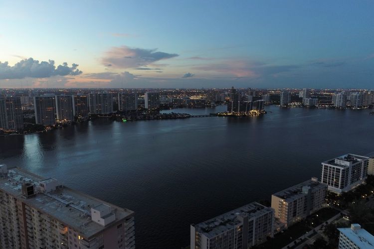 High angle view of buildings by sea against sky during sunset