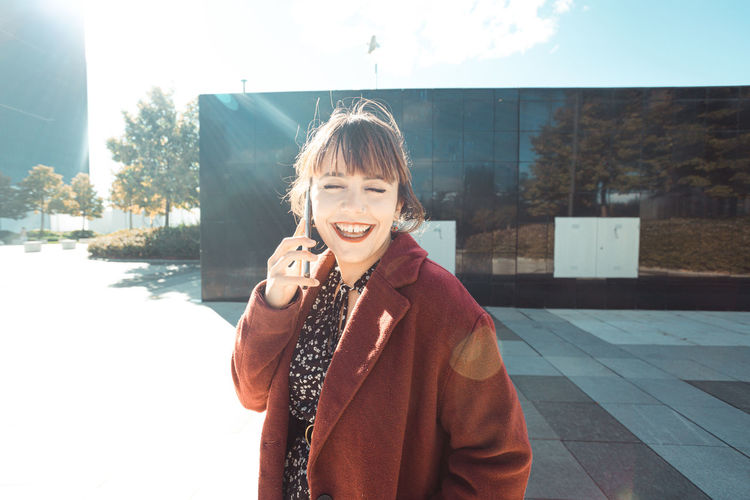 Happy woman talking on smart phone in city