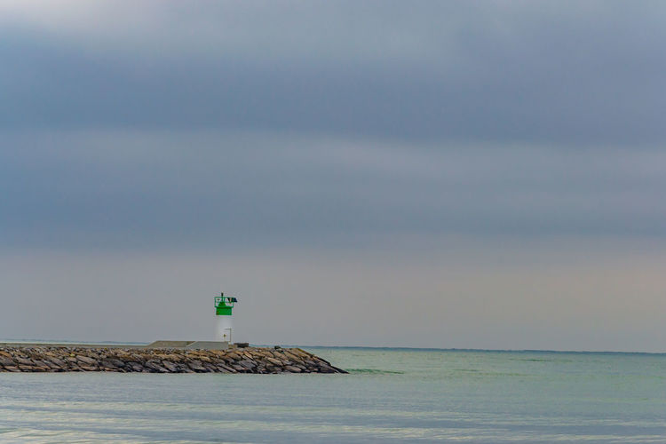 Lighthouse by sea against sky
