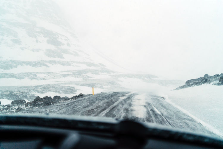 Scenic view of snowcapped mountains seen through car windshield