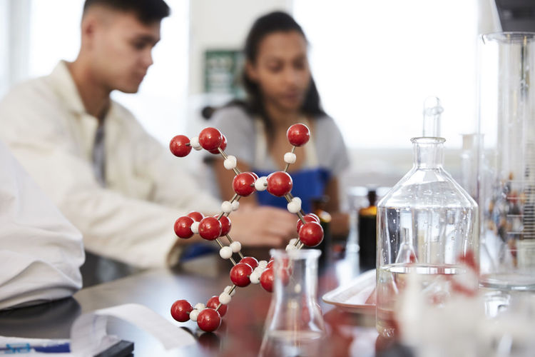 Molecular structure on table against young students in chemistry laboratory