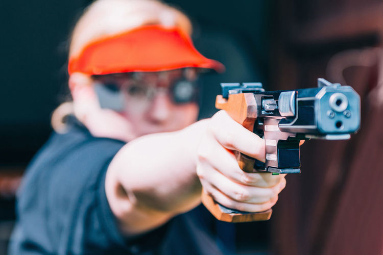 Close-up of woman aiming gun outdoors